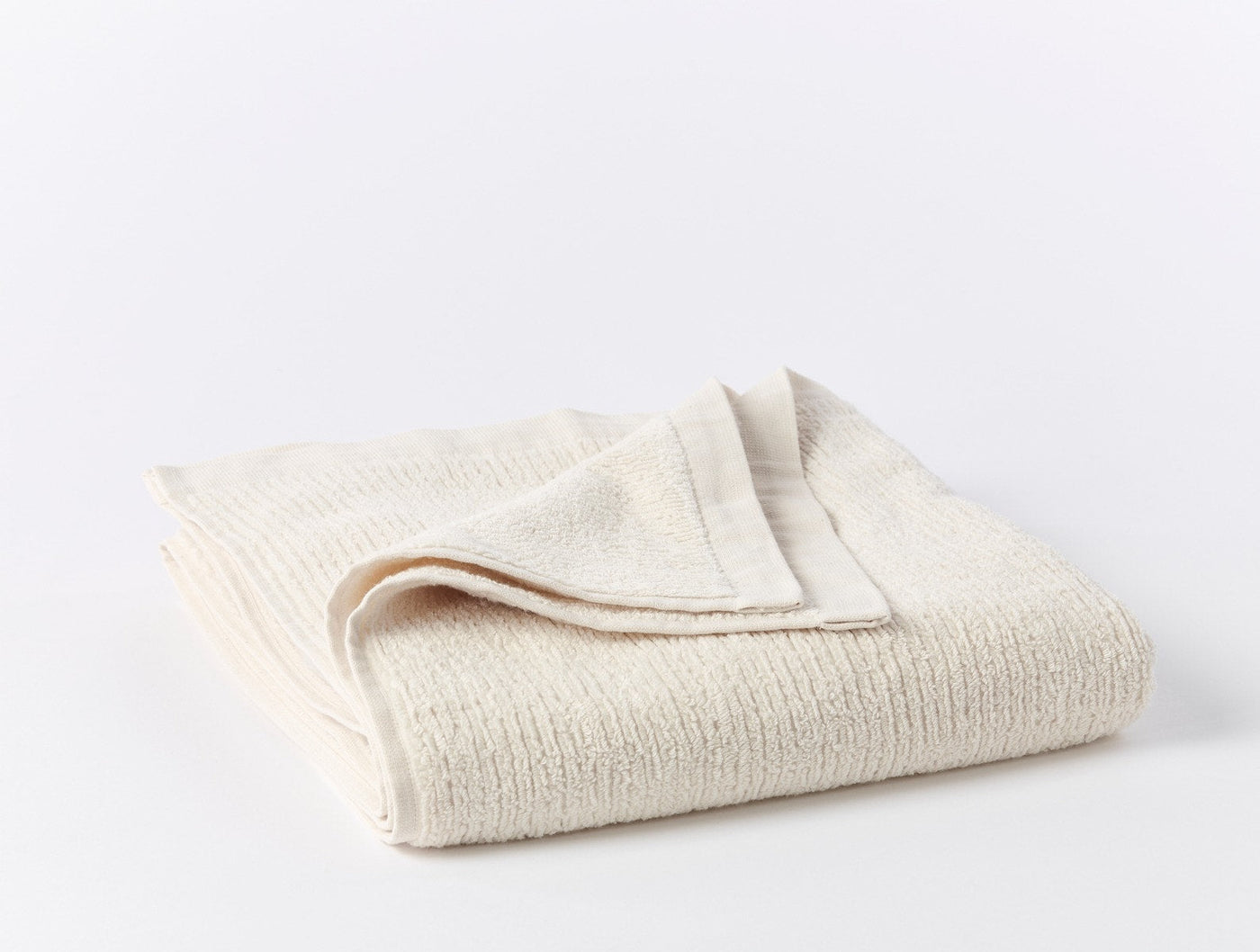Ivory ribbed cotton towel set folded to show textured weave and hemmed edge detail.