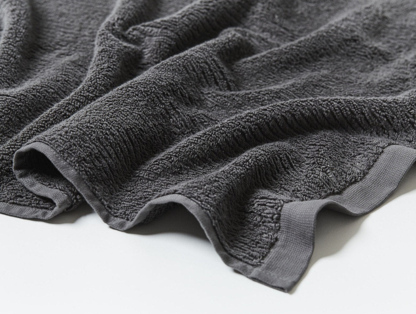 Close-up of Coyuchi Temescal charcoal terry towel showing ribbed border hem detail.
