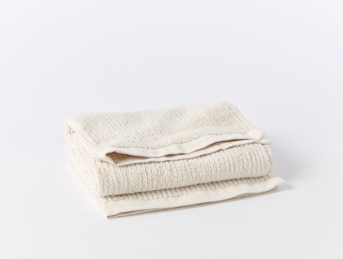Folded ivory ribbed bath towel showing textured weave and hemmed edge detail.