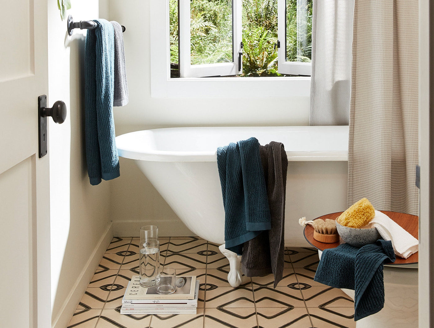 Teal and charcoal ribbed towels styled in a bright bathroom with clawfoot tub.