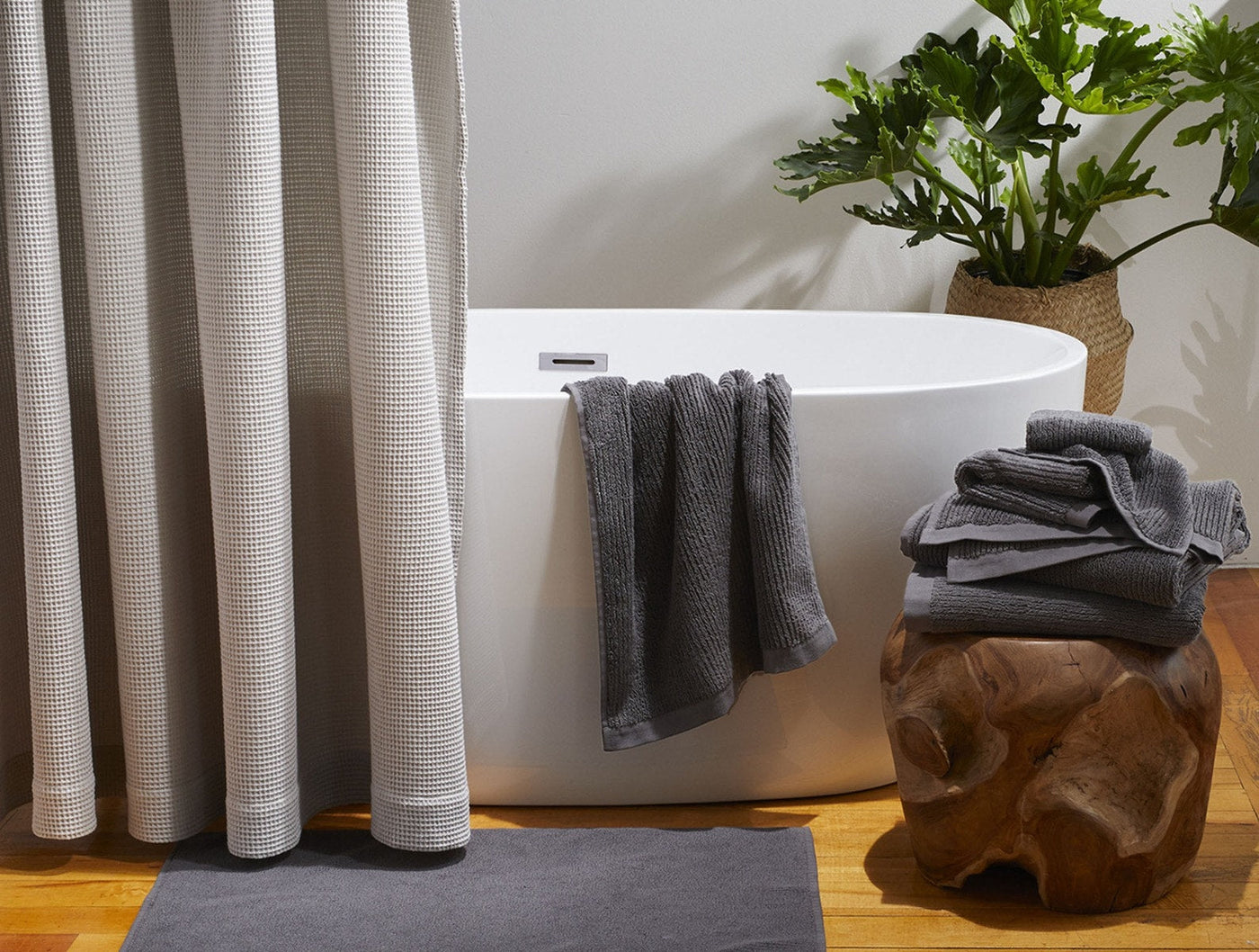 Coyuchi slate grey ribbed bath towels styled in a bathroom with freestanding tub.