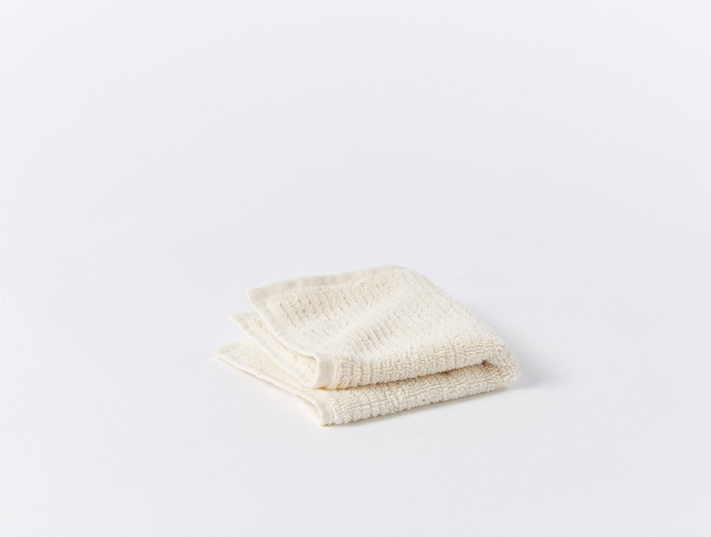 Coyuchi Temescal Ribbed wash cloth folded flat, ivory ribbed cotton terry texture.