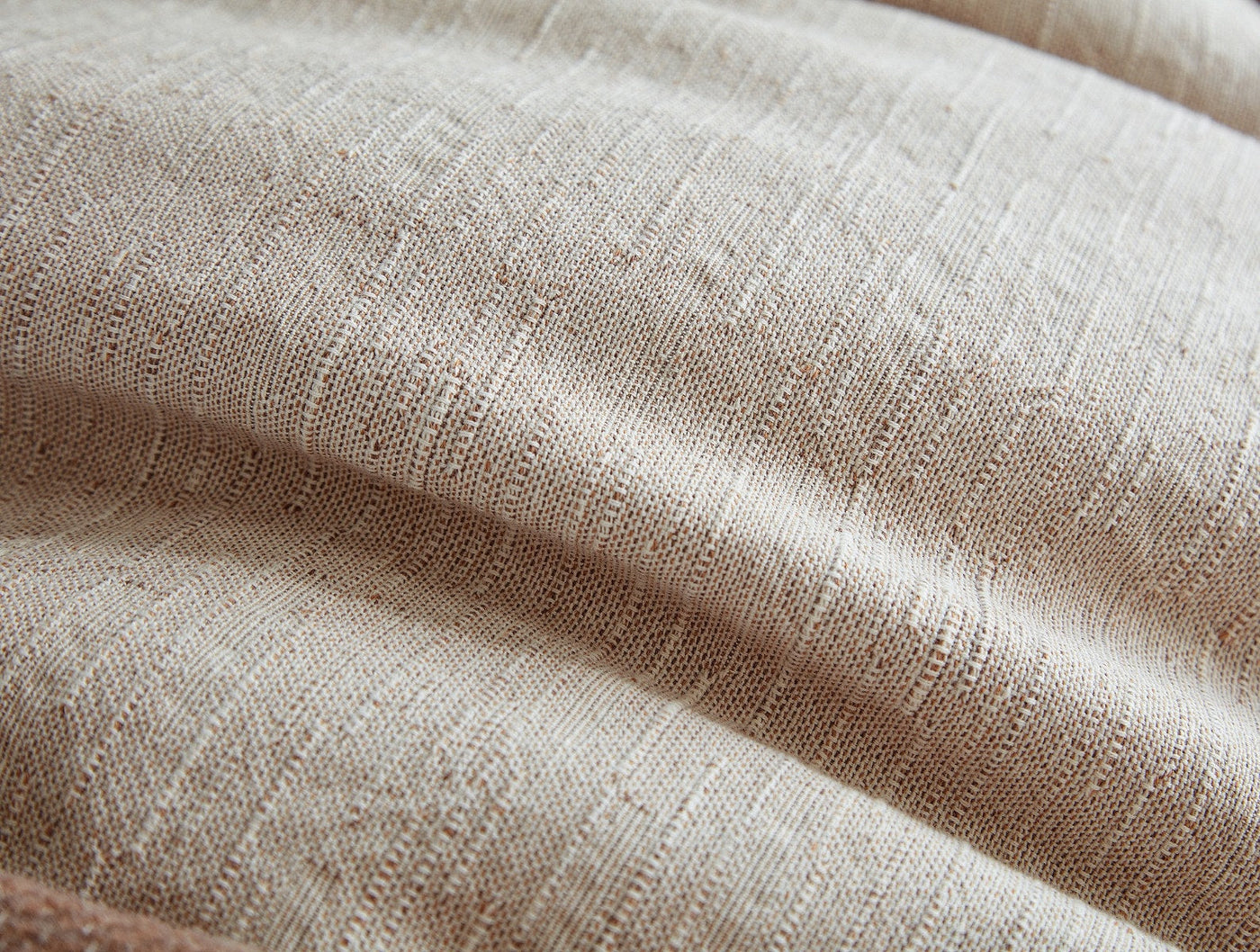 Close-up of oatmeal linen weave texture with soft natural draping and subtle slub detail.