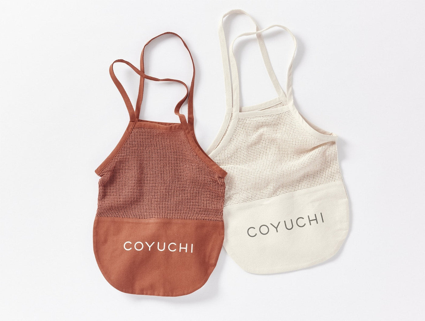 Two Coyuchi Conserve tote bags in terracotta and undyed natural, flat lay.