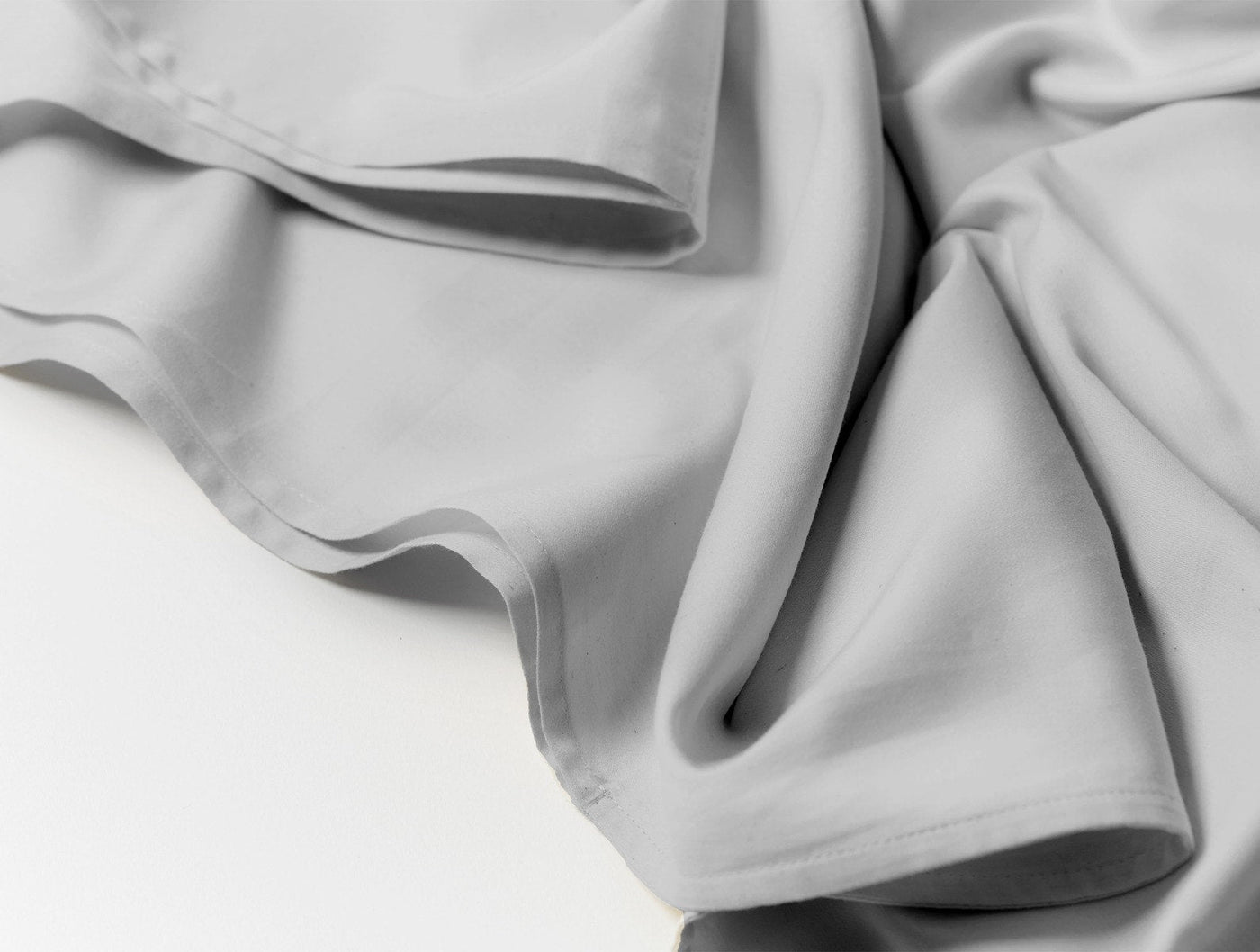 Draped silver Coyuchi Cloud Soft Sateen fabric showing smooth, lustrous texture.