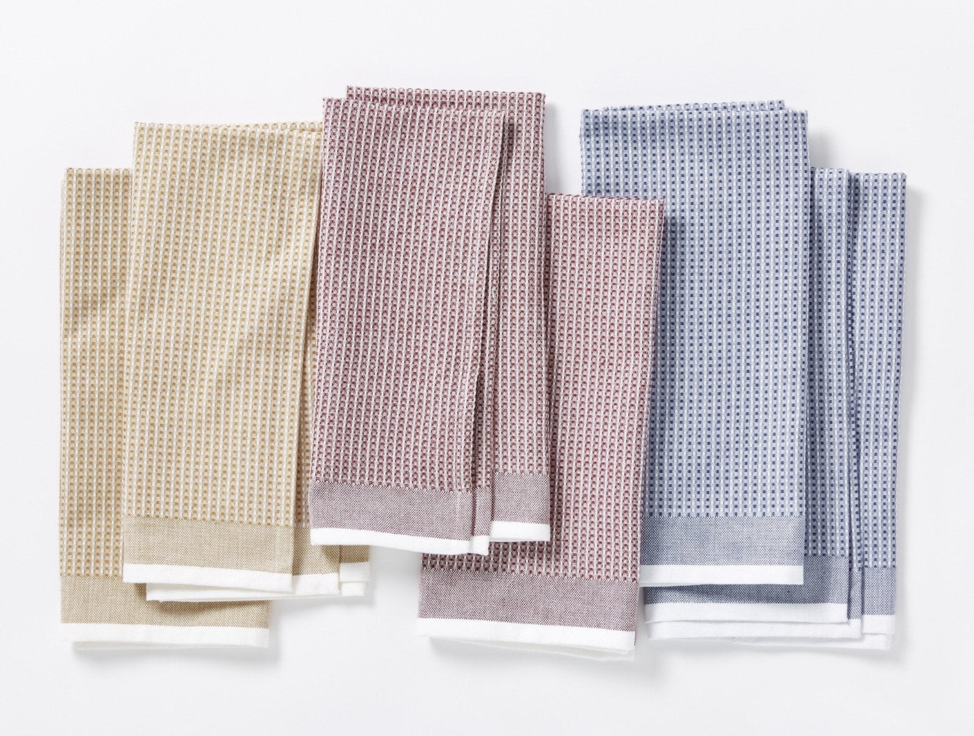Coyuchi waffle kitchen towel sets in sage, mauve, and blue, fanned flat on white.