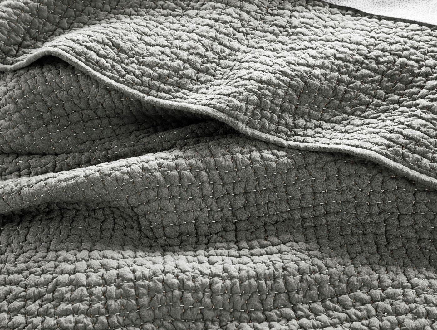 Close-up of Coyuchi Pebbled Handstitched quilt showing textured weave and hand-stitched detail.