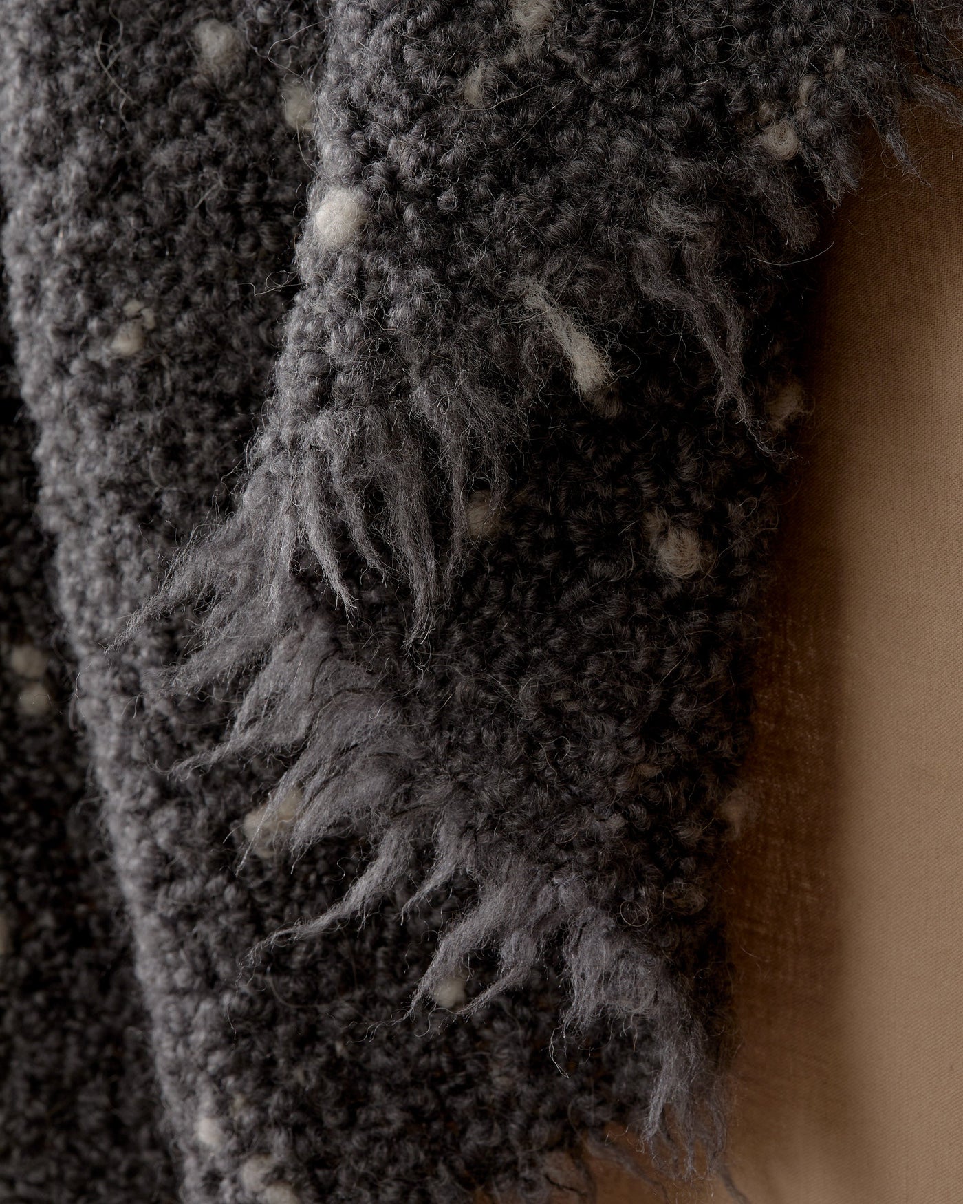 Close-up of charcoal boucle fringe edge with ivory fleck detail on Society Limonta Peg throw.
