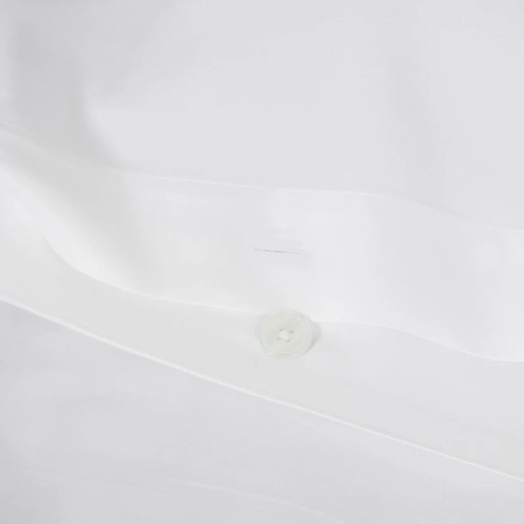 Close-up of the Frette Percale | Duvet Cover by Frette, featuring smooth white 100% cotton fabric with a single white button and a glimpse of the buttonhole for a refined finish.