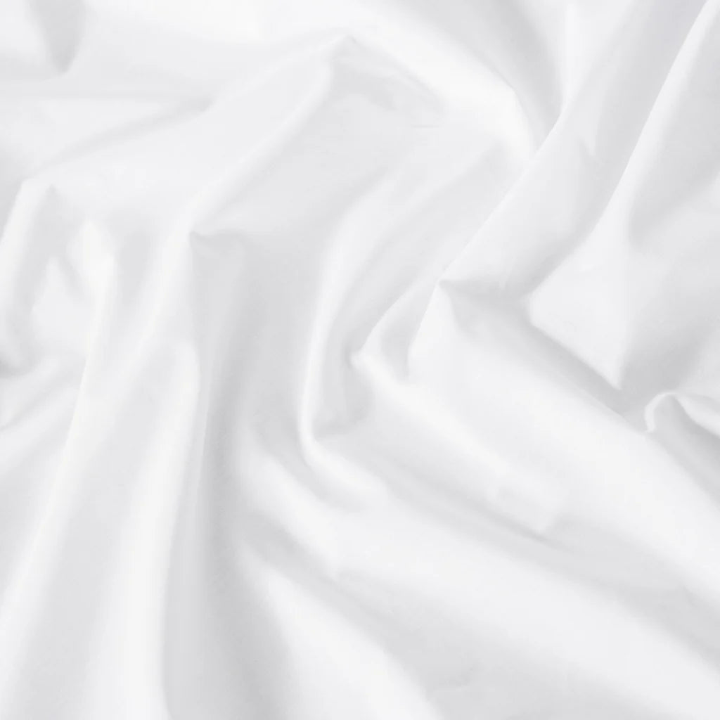 A close-up of the Frette Percale | Duvet Cover by Frette, showcasing its white, breathable long-staple cotton with smooth texture, soft folds, and gentle creases.