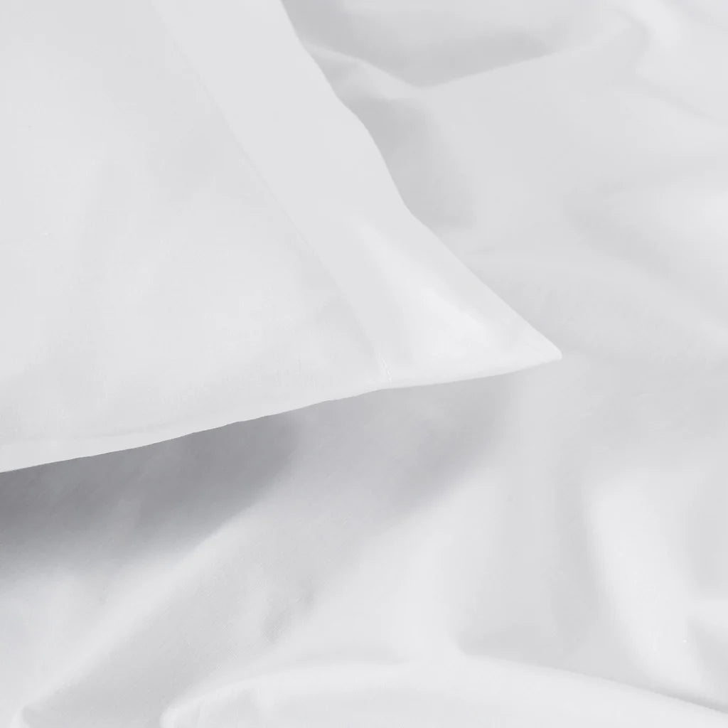 A close-up of the Frette Percale | Pillowcase Set by Frette, featuring smooth, breathable fabric in white with subtle folds and creases.