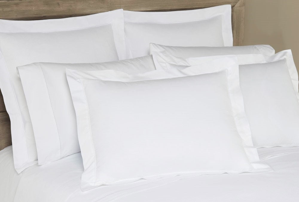 Close-up of white Home Treasures Polycotton pillow shams with tailored flanged edges on a made bed.