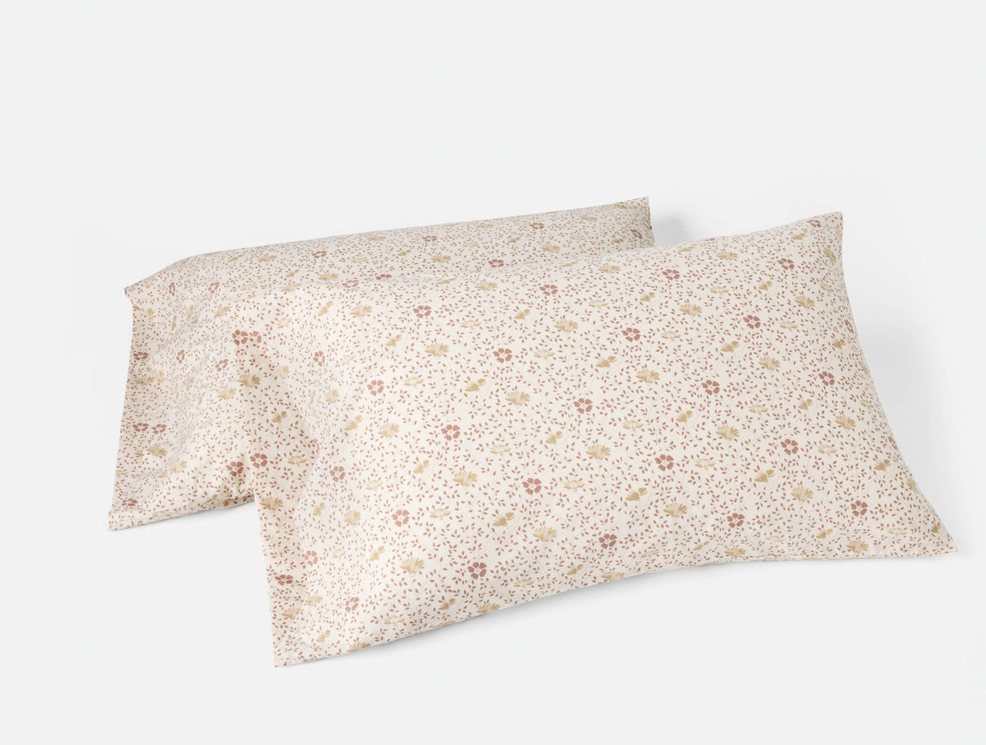 Two Coyuchi ivory percale pillowcases with small scattered ditsy floral print in blush and gold.