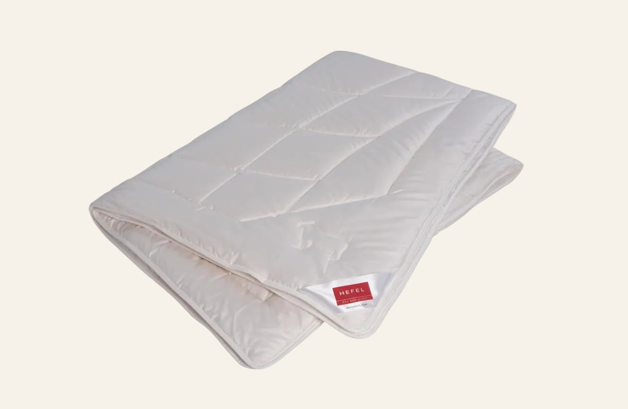 Folded white quilt with a red label on a white background