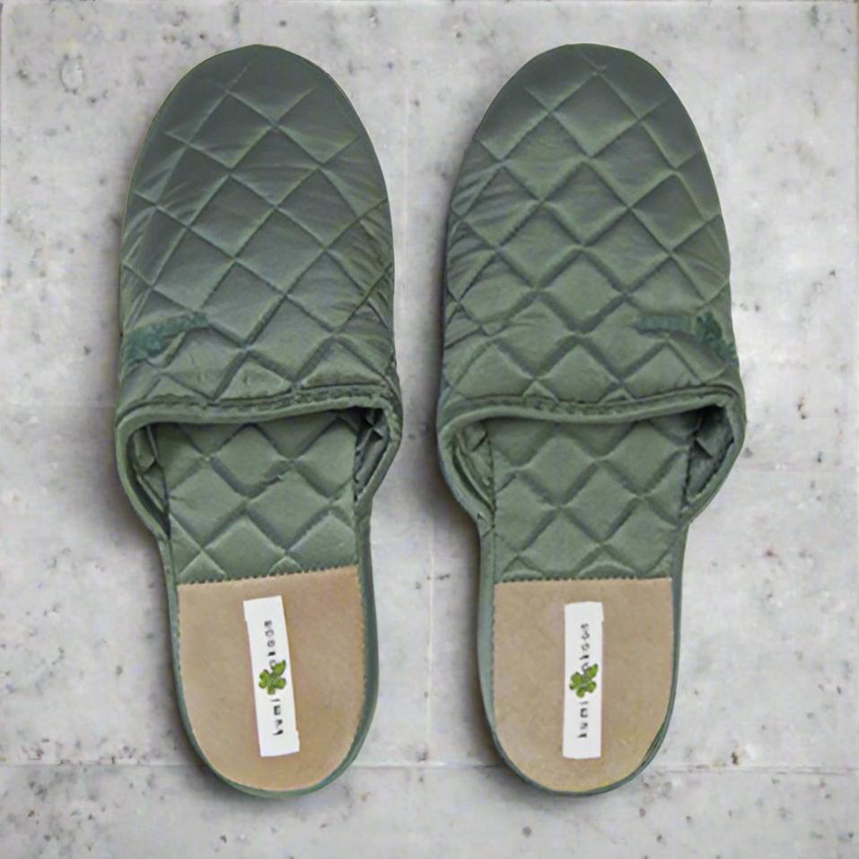 A pair of Kumi Kookoon Quilted Silk Slippers in green are displayed side by side on a light gray marble surface.