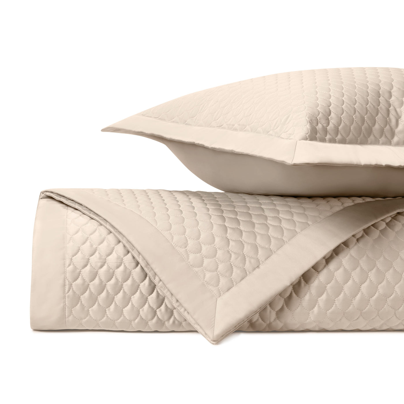 Close-up of Home Treasures Raindrop quilted ivory coverlet and sham with scallop pattern.