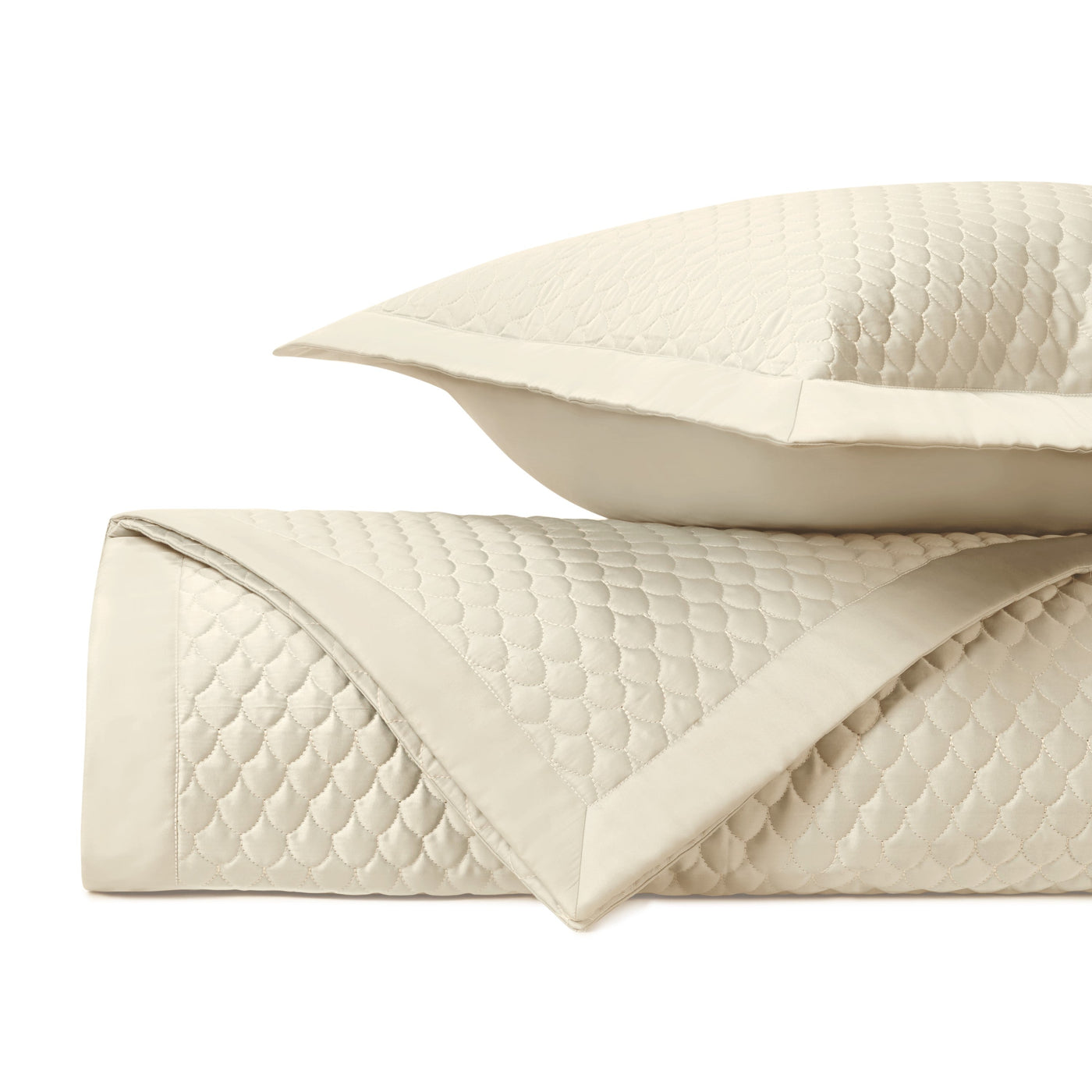 Close-up of ivory quilted fabric with scalloped raindrop pattern and satin border trim.