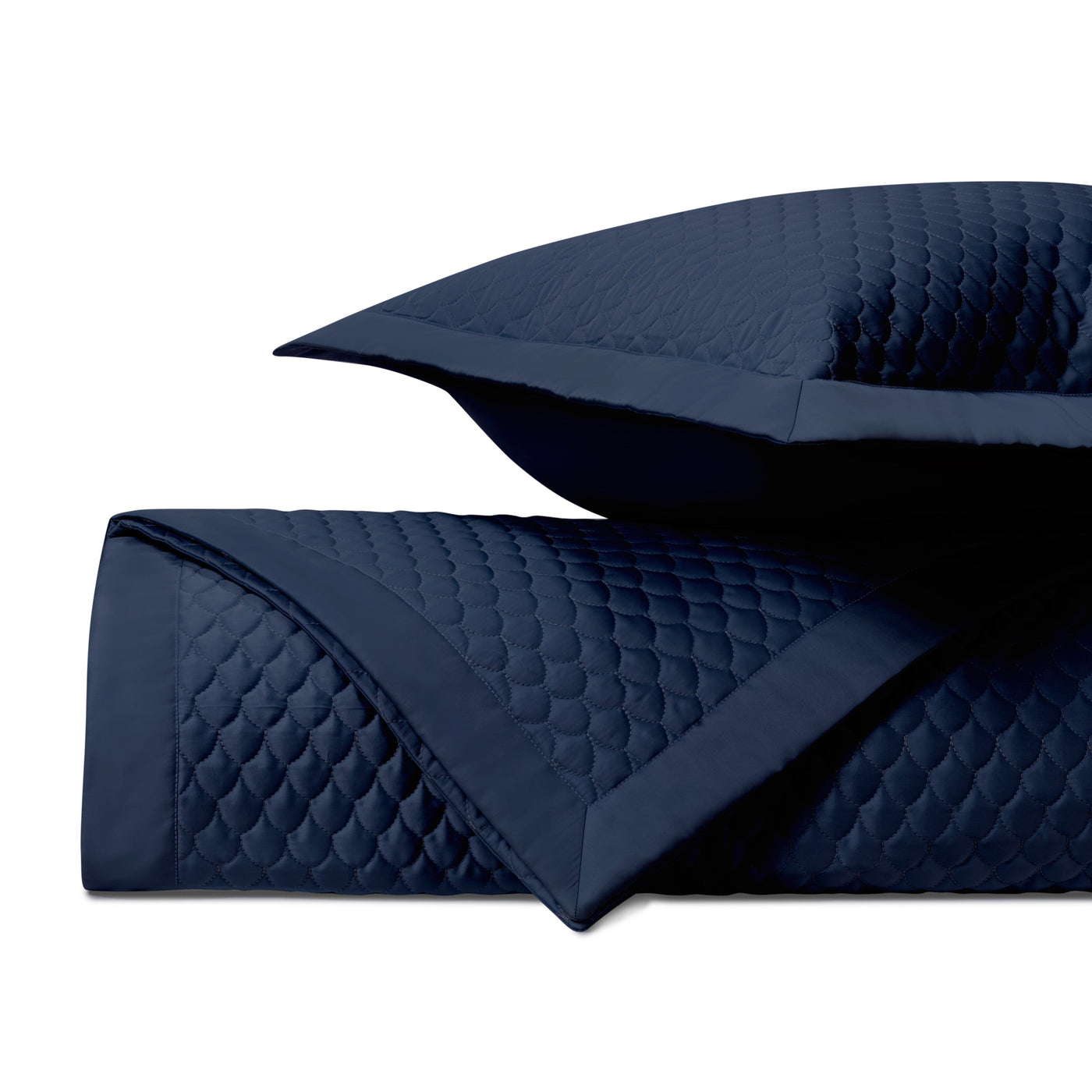 Close-up of navy quilted raindrop-pattern coverlet with coordinating sham and border detail.