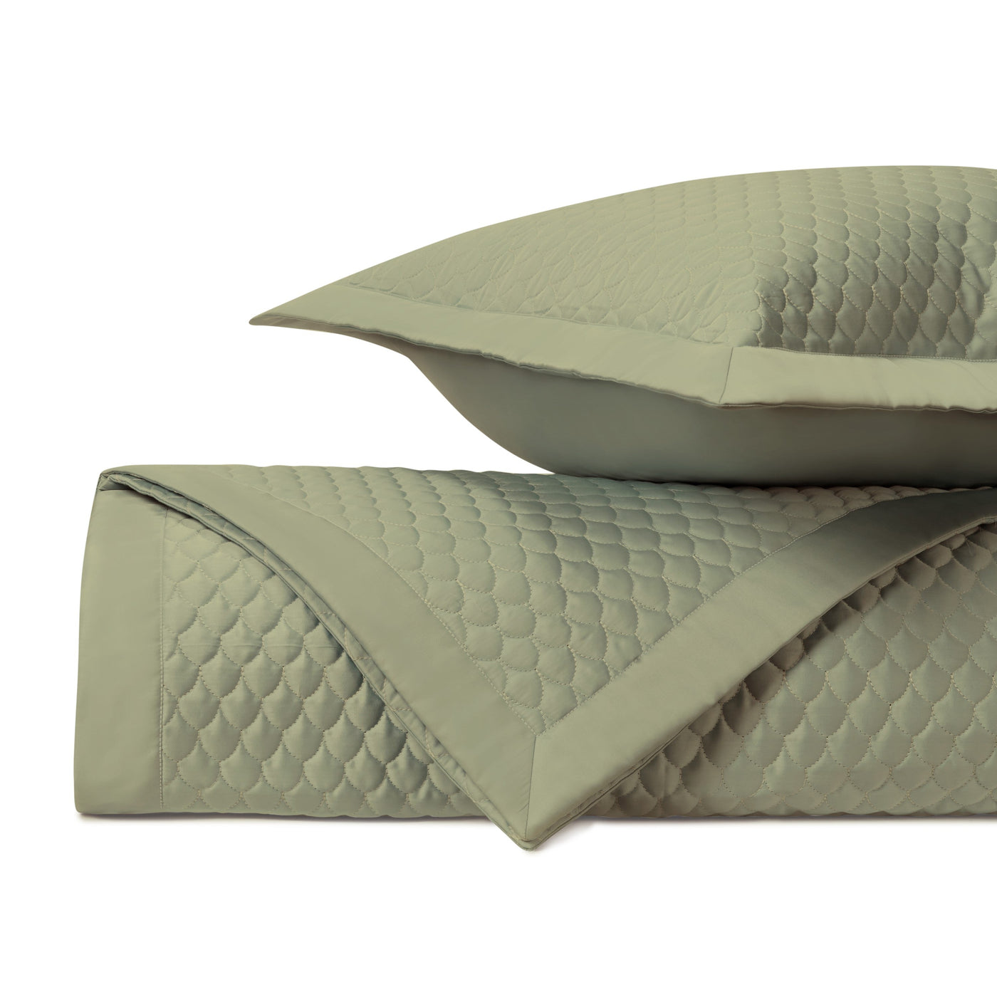 Close-up of sage quilted raindrop-pattern coverlet and sham with mitered border trim.