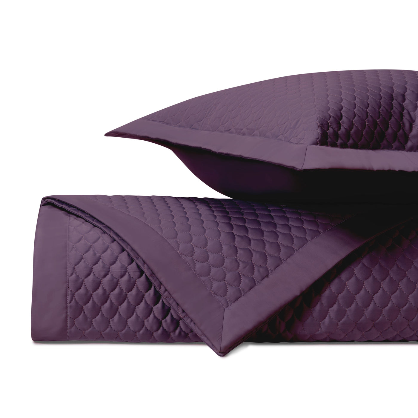 Close-up of deep plum quilted fabric with scalloped raindrop stitching pattern and flat border edge.