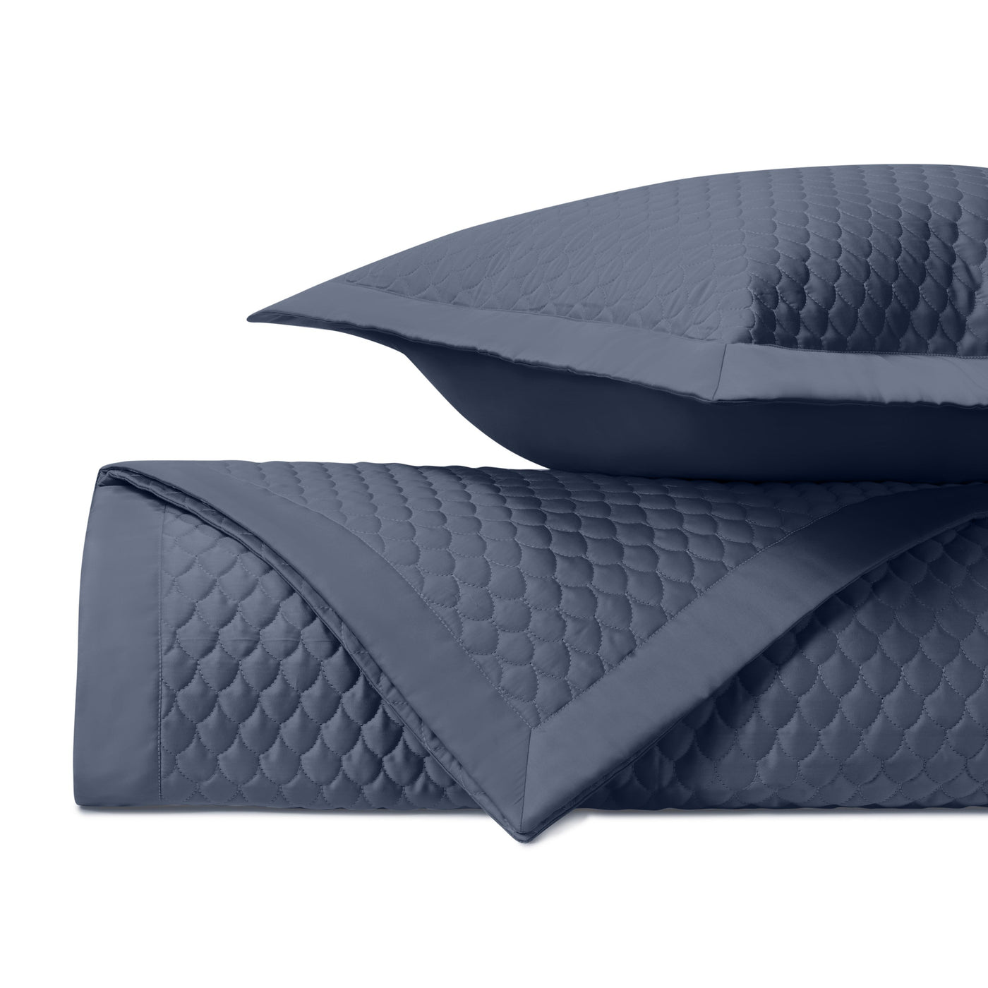 Close-up of navy blue quilted coverlet with scalloped raindrop stitching pattern and sham.