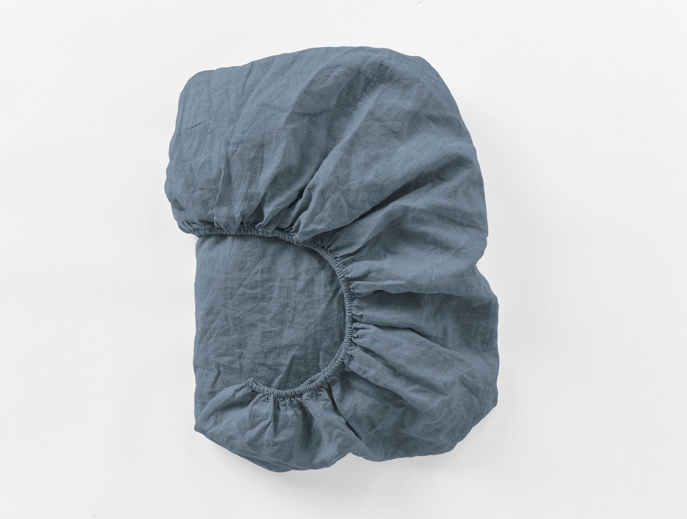 Coyuchi Relaxed Linen fitted sheet folded to show elasticated corner, slate blue.