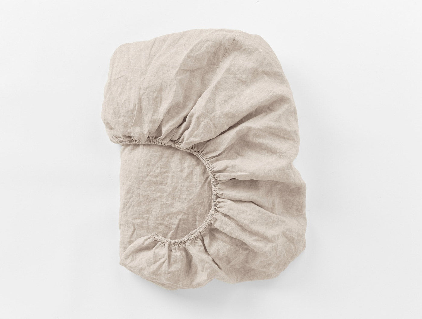 Fitted sheet folded to show elastic corner detail, natural linen, relaxed texture.