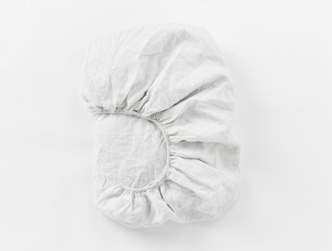 Coyuchi Relaxed Linen fitted sheet in white, folded to show elasticated corner detail.