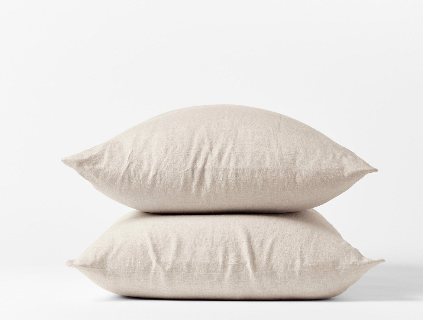 Two stacked Coyuchi Relaxed Linen pillowcases in natural, showing soft drape and woven texture.
