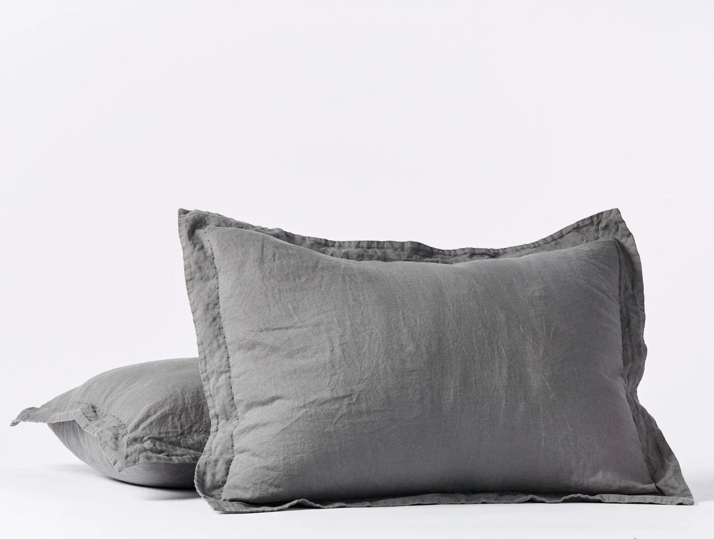 Close-up of two stacked Coyuchi Relaxed Linen shams in slate grey with frayed edges.
