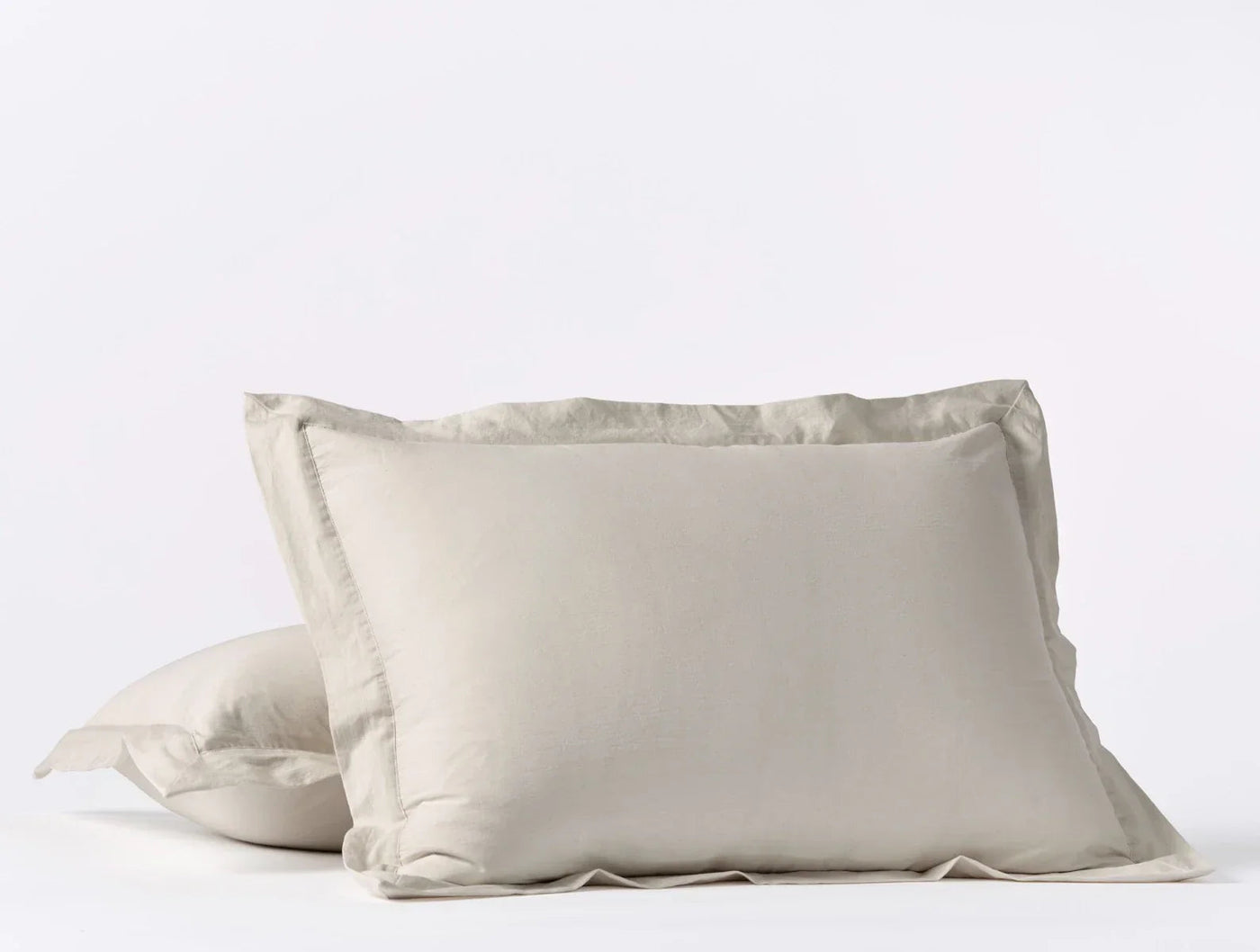 Two stacked Coyuchi Cloud Soft Sateen shams in warm sand with a classic flange border.
