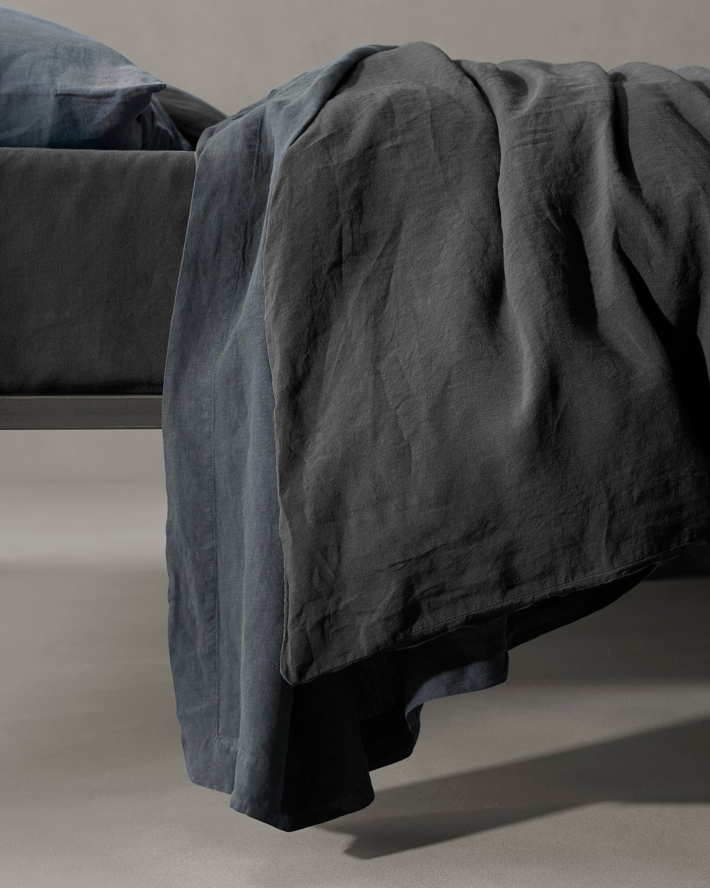 Society Limonta Rem duvet cover in slate linen, draped over bed foot showing natural texture.