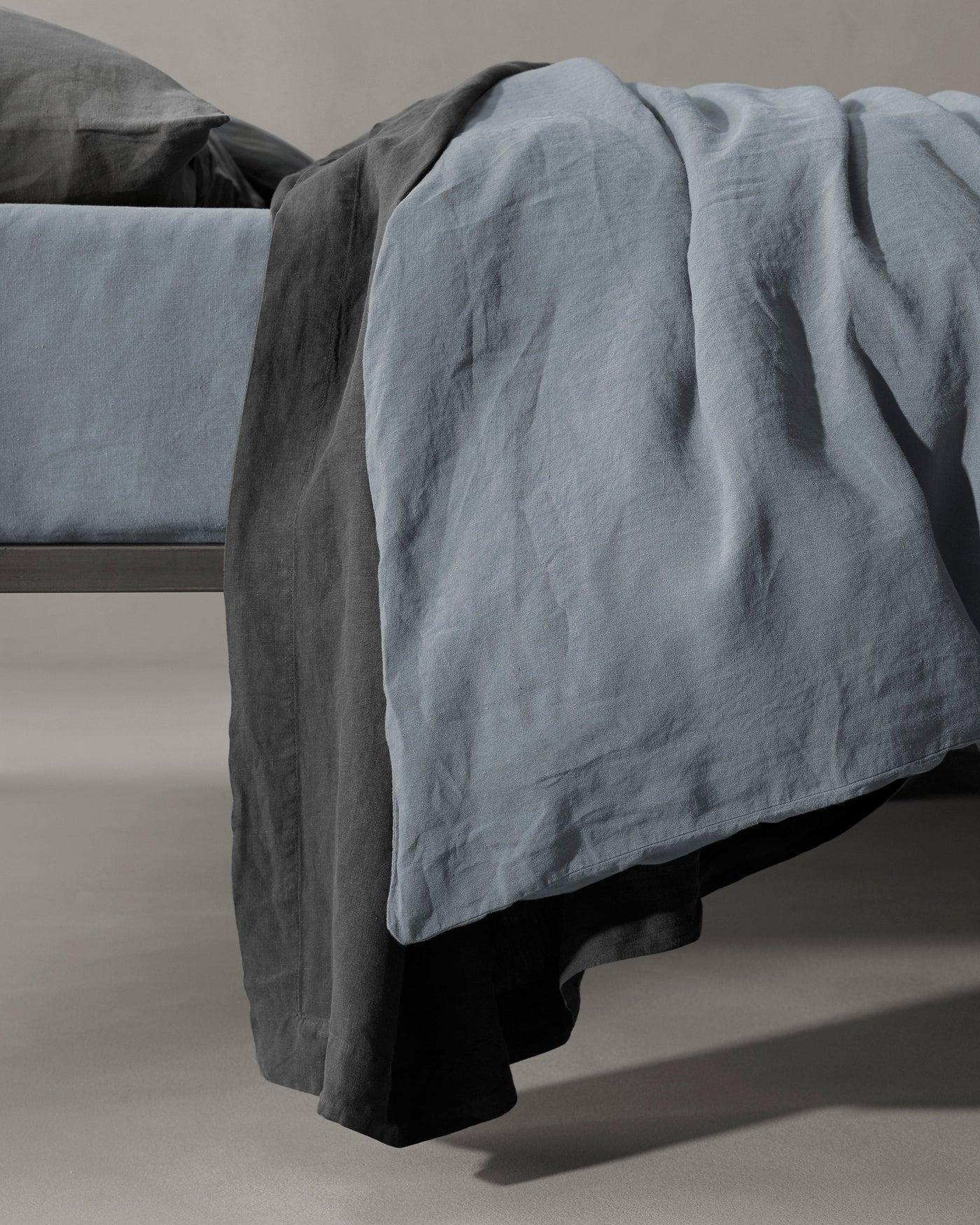 Society Limonta Rem duvet cover in slate blue washed linen draped over bed foot.