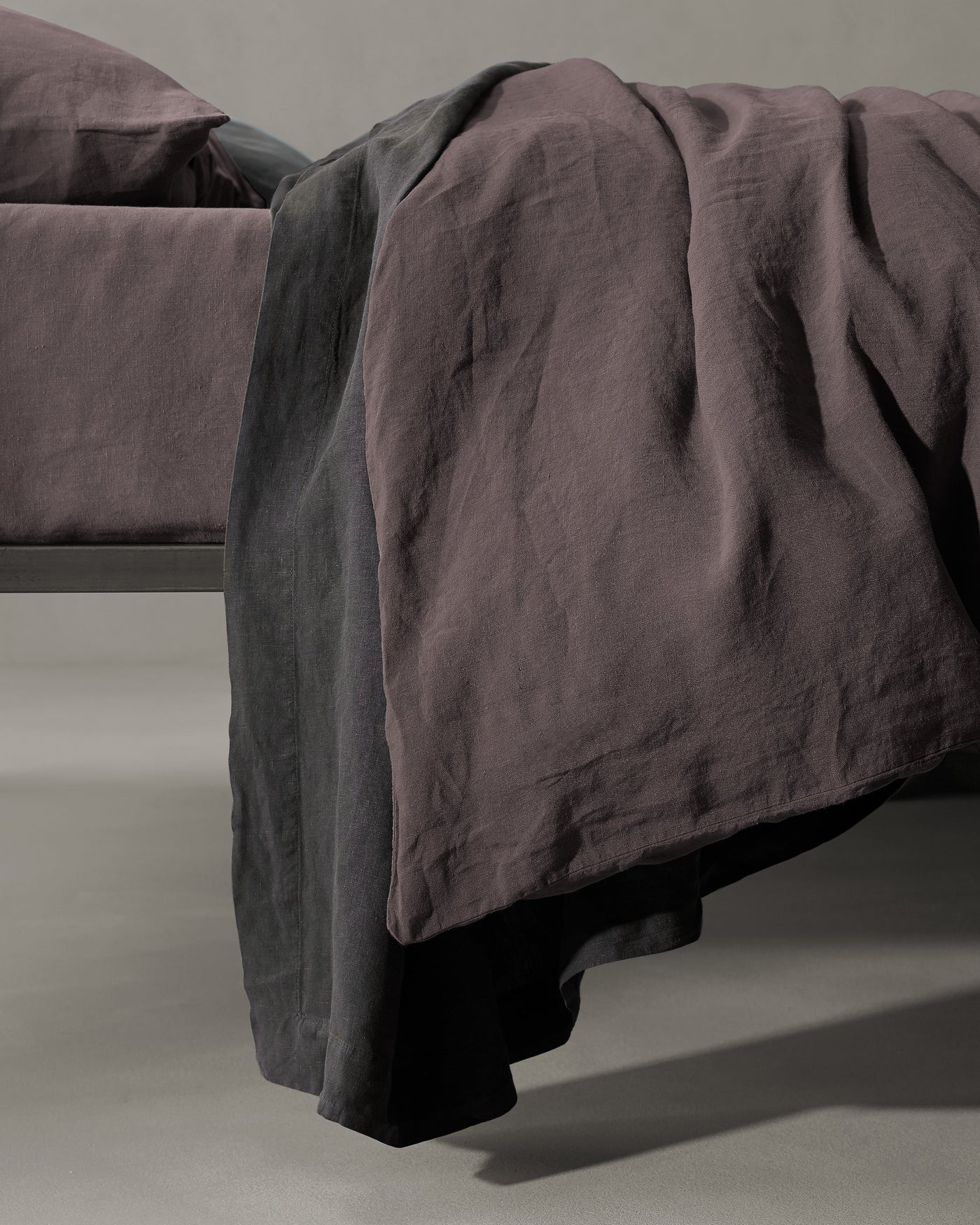 Society Limonta Rem duvet cover in plum linen, draped over bed corner showing natural texture.
