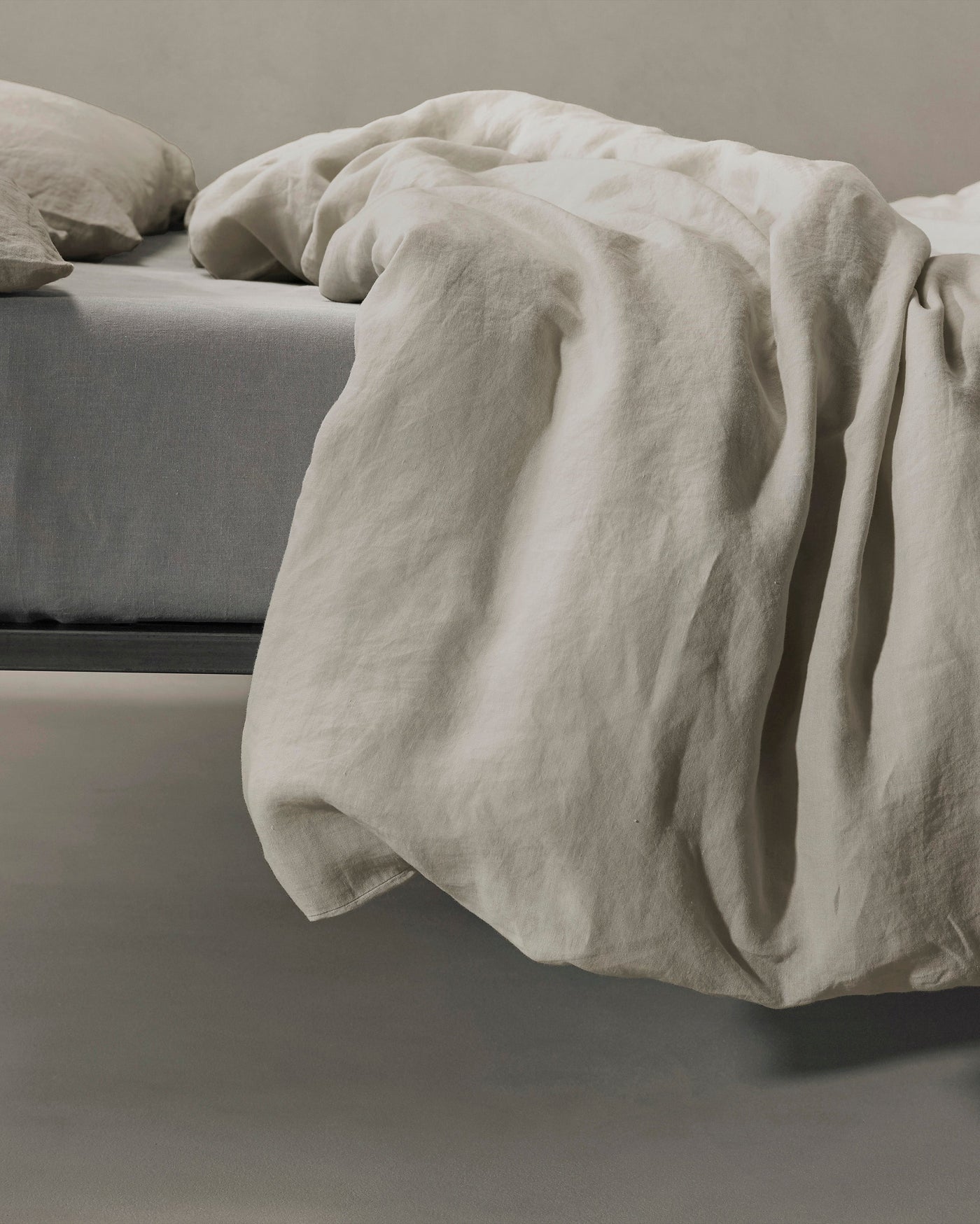 Close-up of Society Limonta Rem duvet cover in natural linen draping off bed edge.