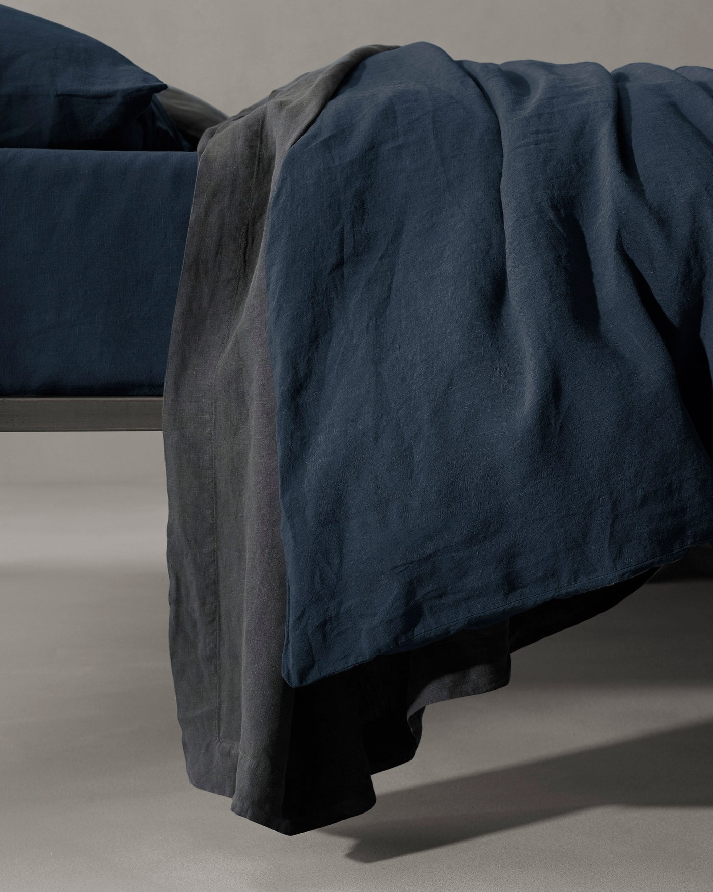 Close-up of midnight blue and charcoal linen duvet draped over bed foot.