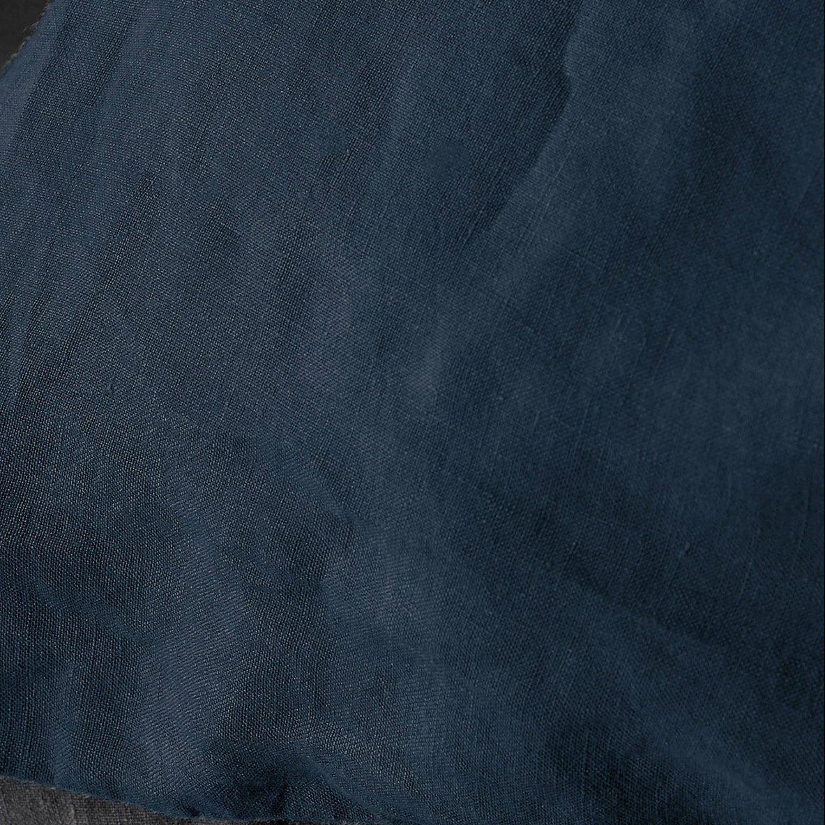 Close-up of midnight blue linen duvet cover showing relaxed texture and natural creasing.