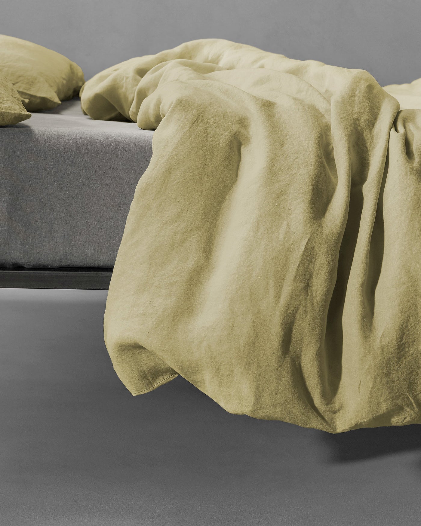 Society Limonta Rem duvet cover in sage linen, draped over bed edge with natural texture visible.