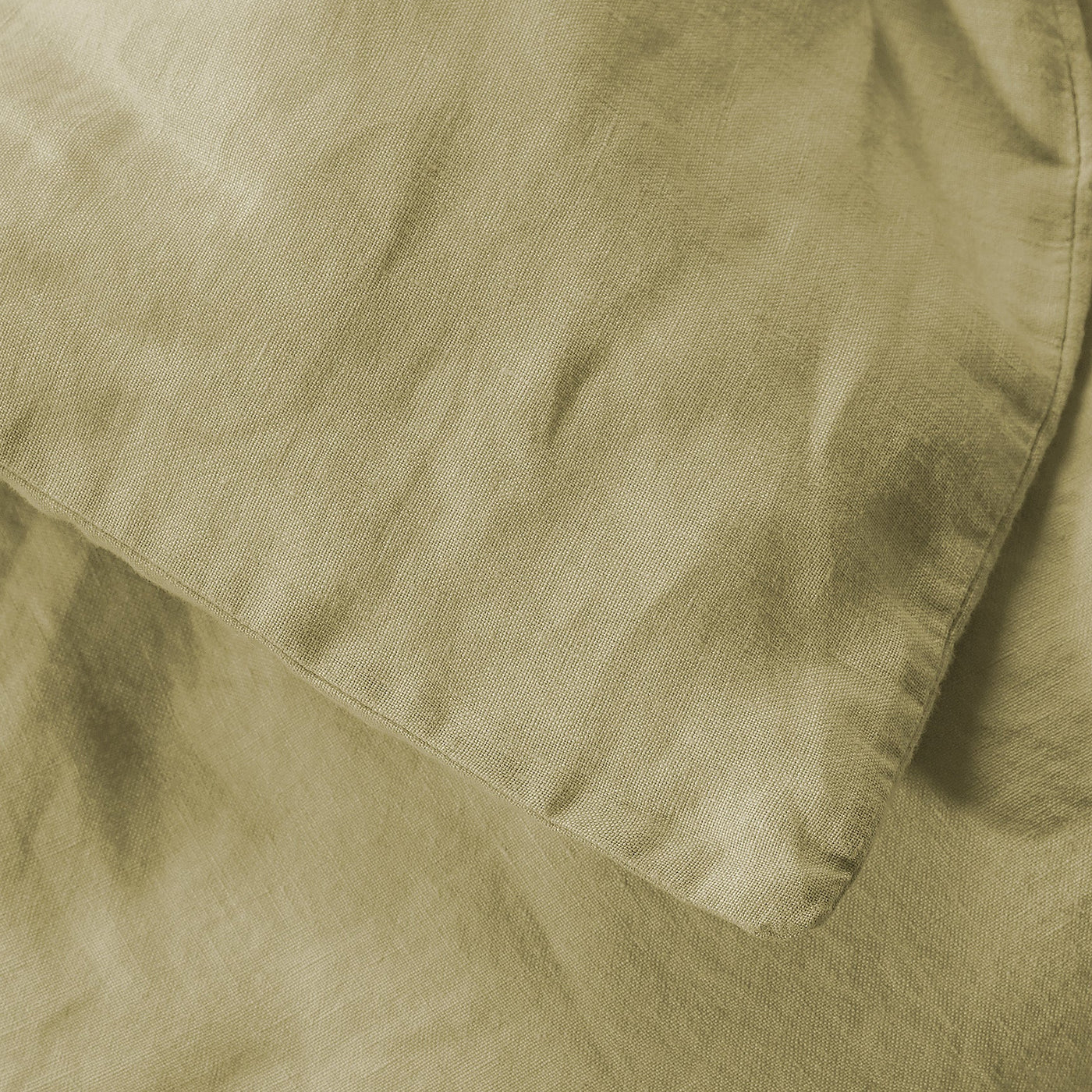 Close-up of sage linen duvet cover showing relaxed texture and hemmed edge detail.