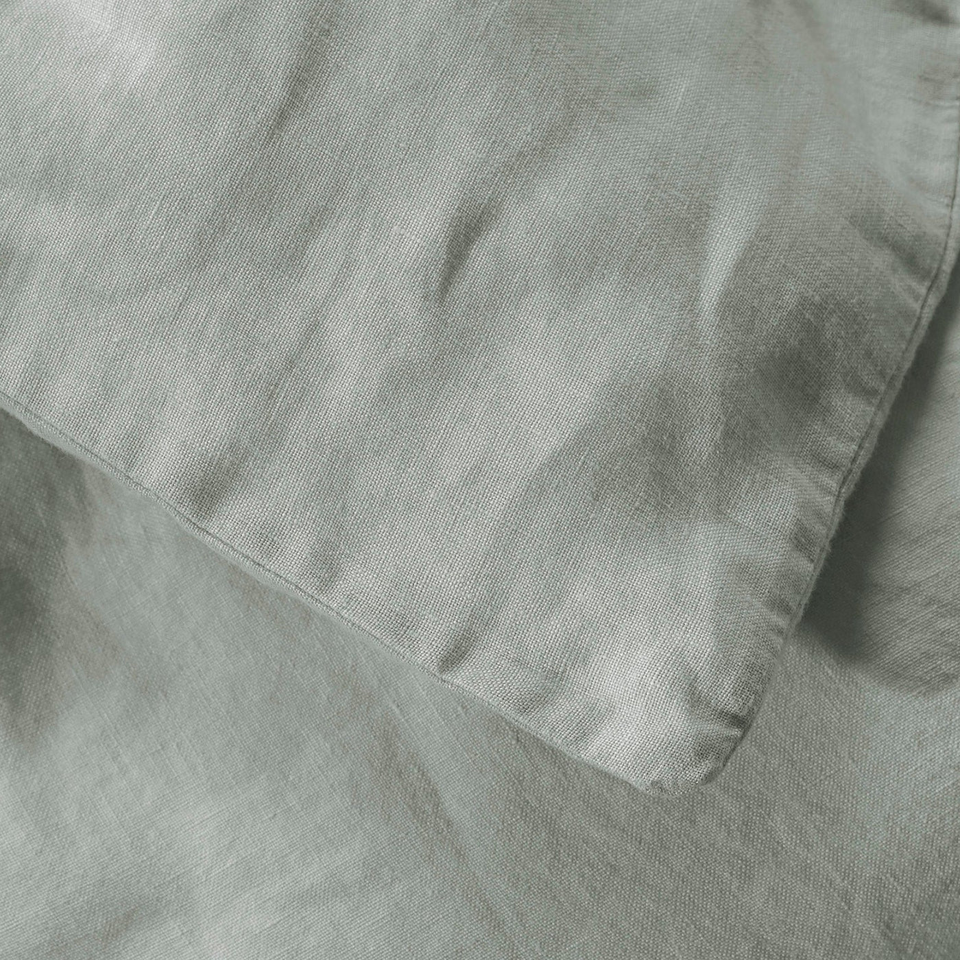 Close-up of sage linen fabric showing natural texture and subtle sheen.