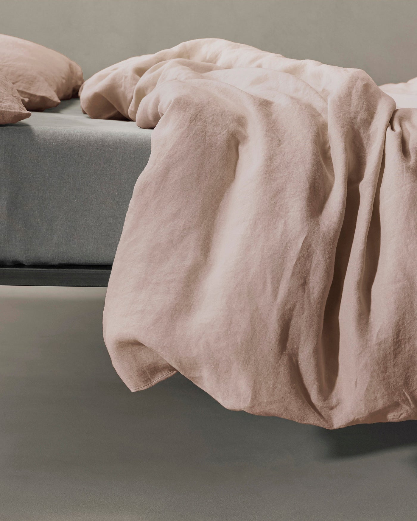 Blush linen duvet cover draped loosely over bed edge, showing relaxed texture.