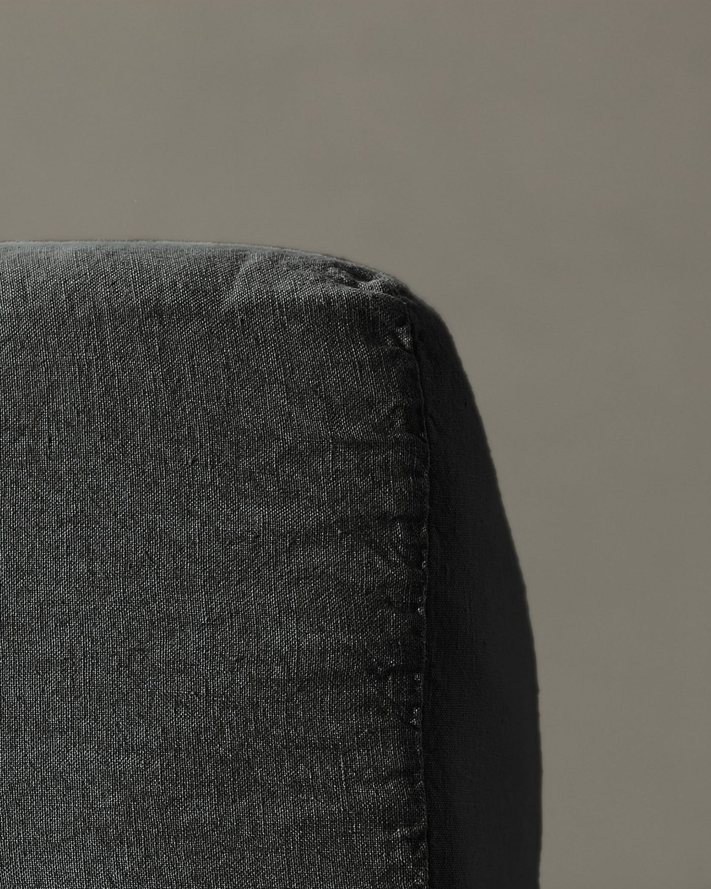 Close-up of charcoal linen fitted sheet corner seam detail.