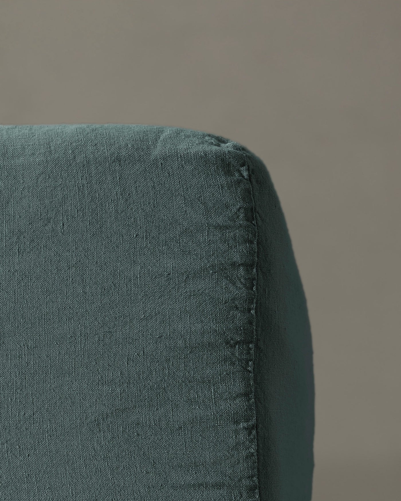Close-up of teal linen fitted sheet corner seam detail.