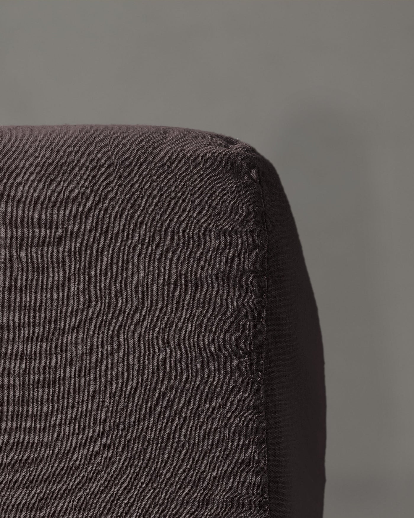 Close-up of charcoal linen fitted sheet corner showing natural texture and seam detail.