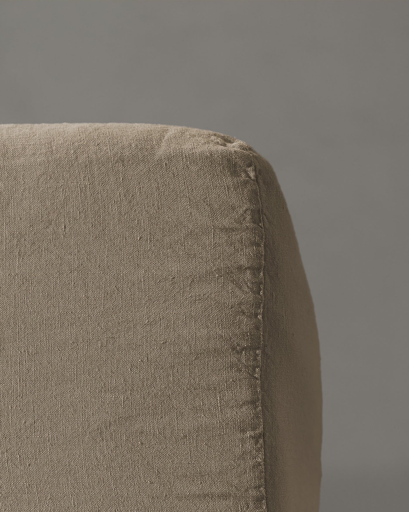 Close-up of taupe linen fitted sheet corner seam detail.