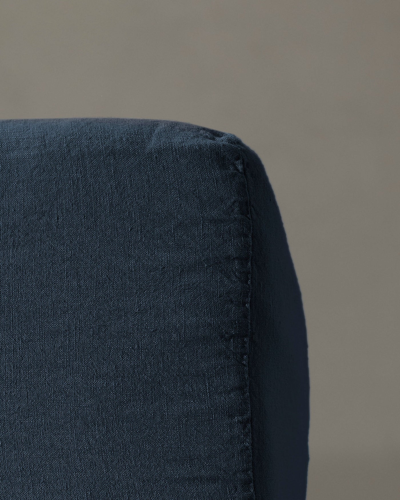 Close-up of midnight blue linen fitted sheet corner seam detail.