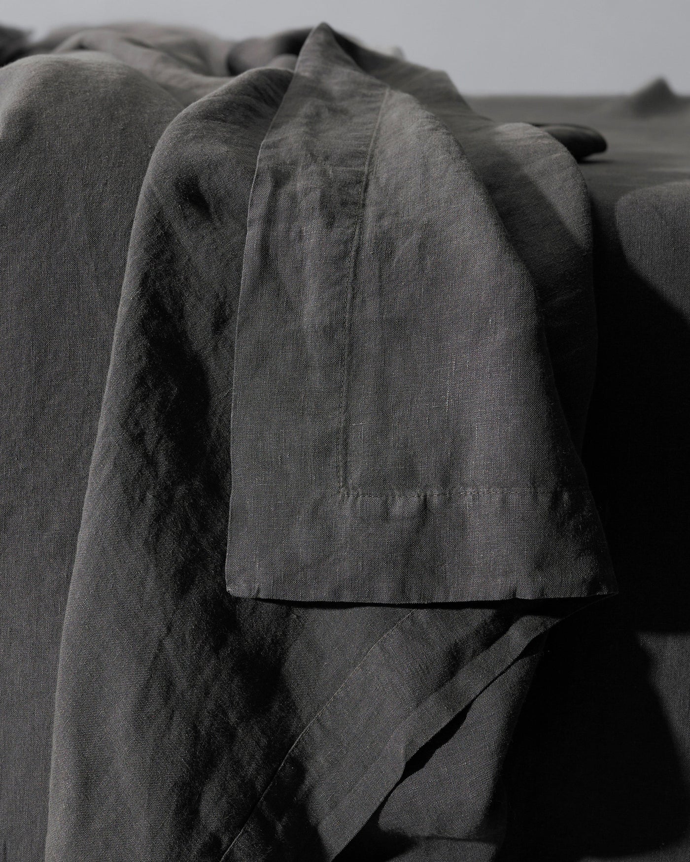 Close-up of Society Limonta Rem flat sheet hem detail in charcoal linen.