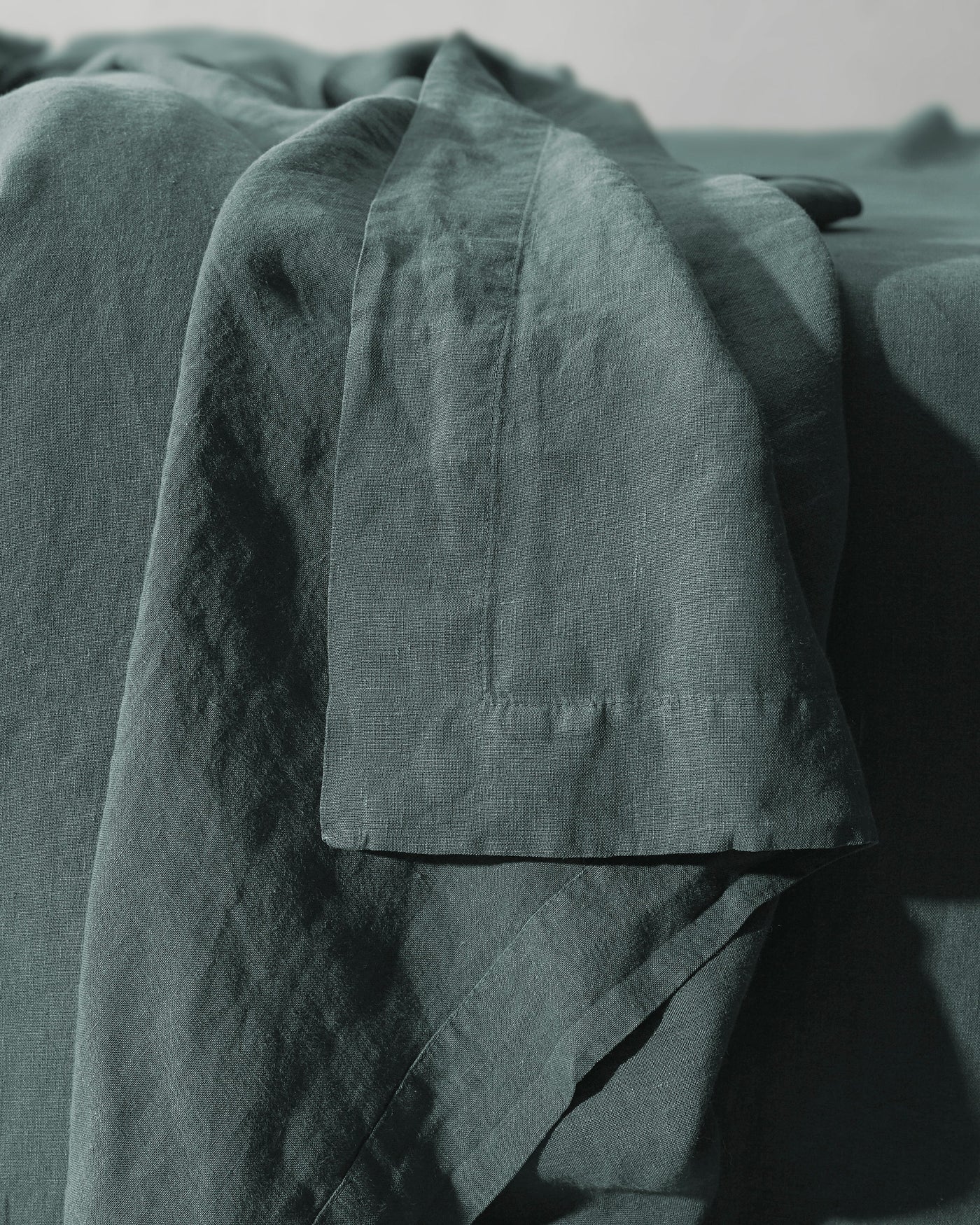 Close-up of Society Limonta Rem flat sheet hem detail in deep sage linen.
