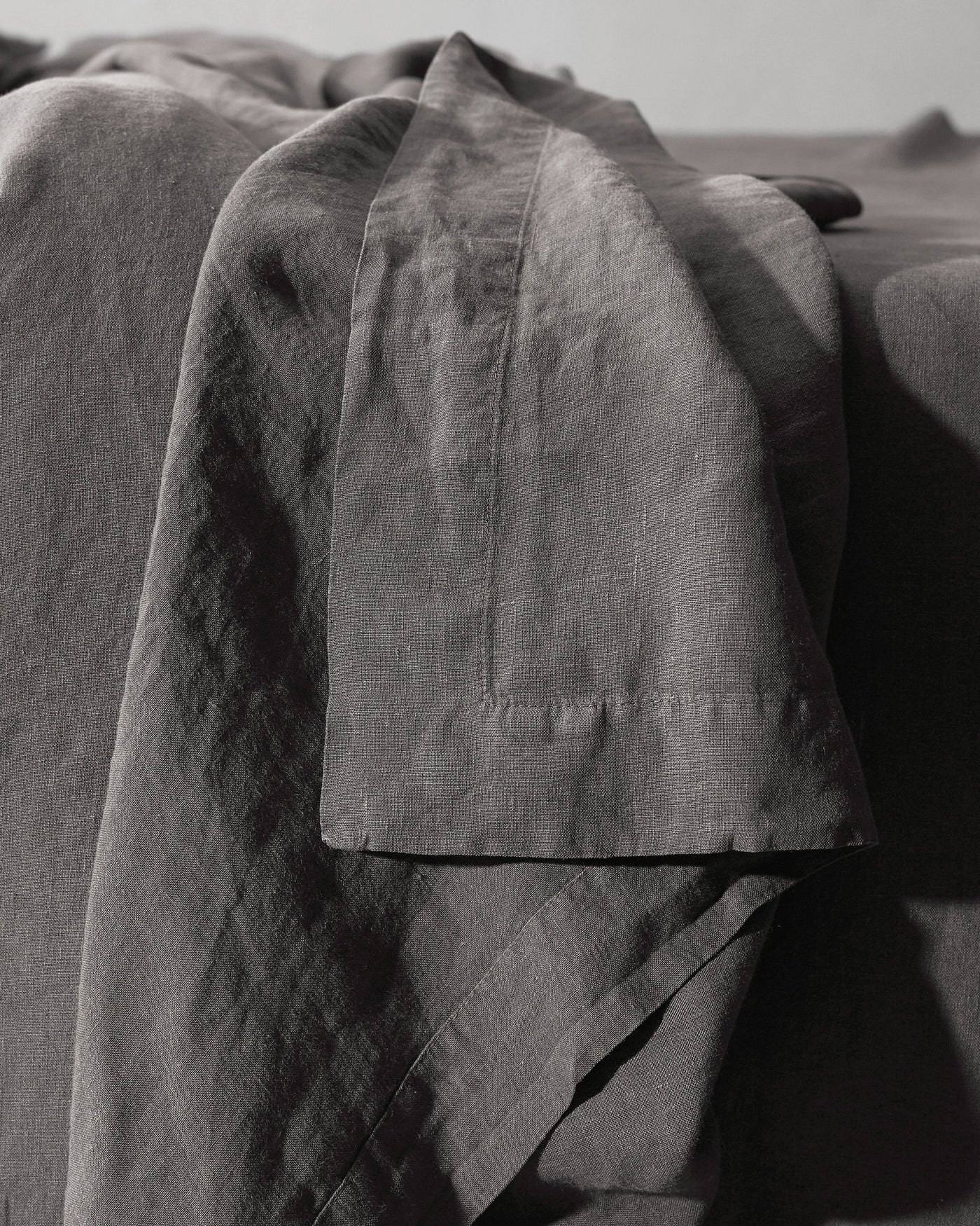 Close-up of Society Limonta Rem flat sheet hem detail in charcoal linen.