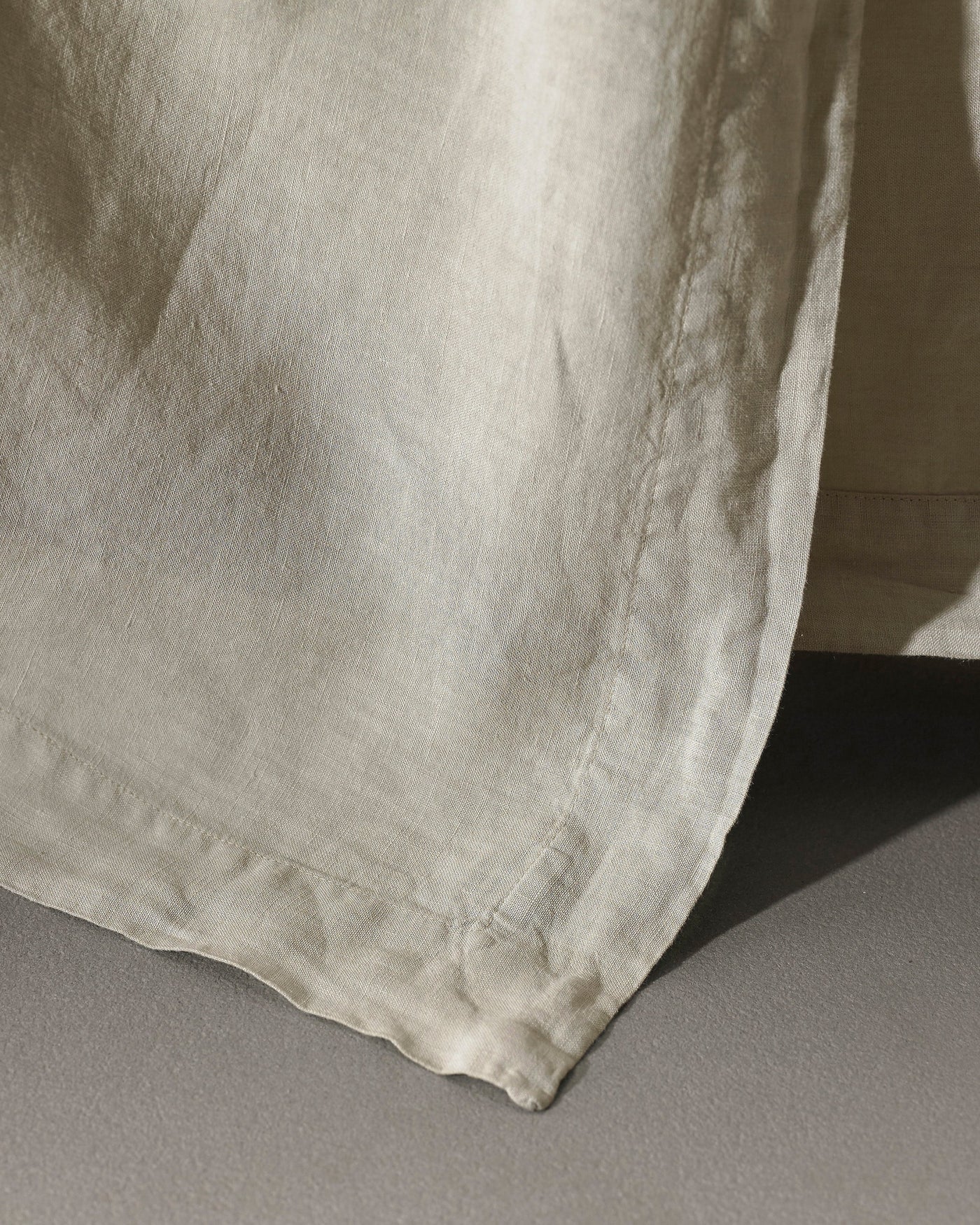 Close-up of Society Limonta Rem flat sheet hem in natural linen, stitched border detail visible.